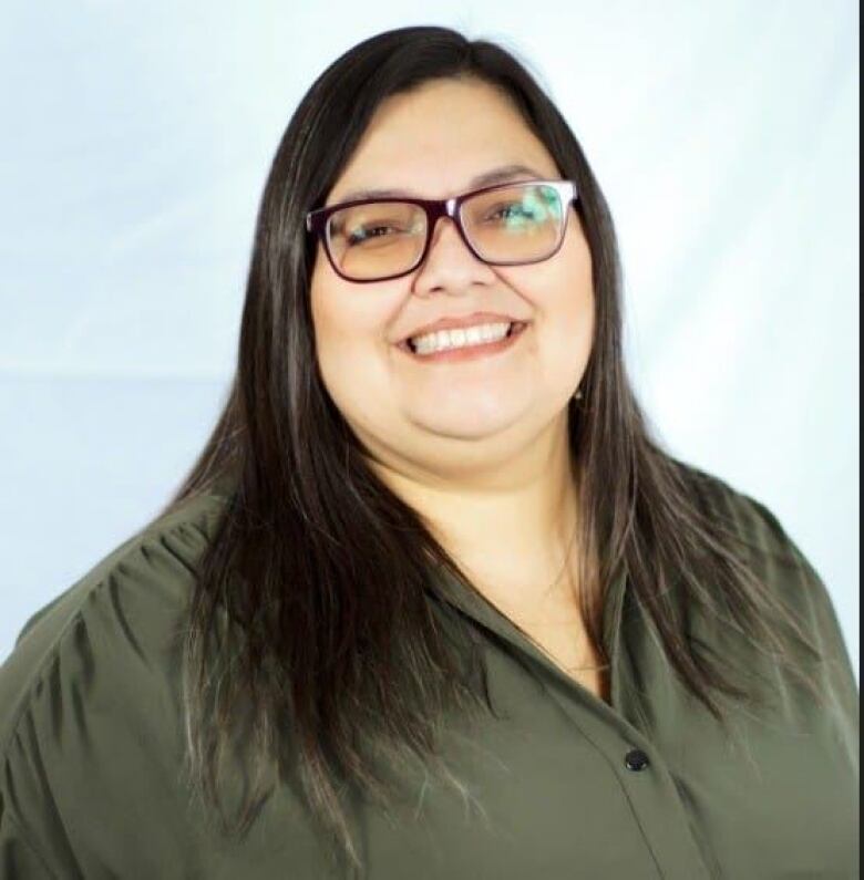 A woman wearing glasses smiles.