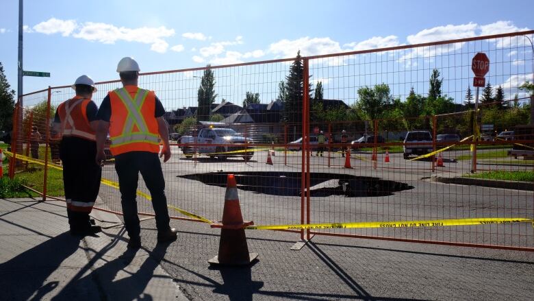 Construction workers are pictured outside of a fenced area.