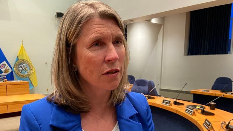 A woman wears a blue jacket while standing in the Fredericton city council chambers.