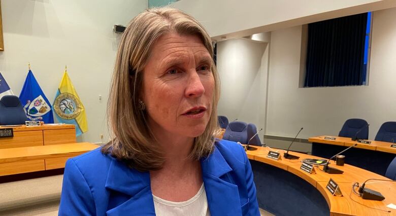 A woman wears a blue jacket while standing in the Fredericton city council chambers.