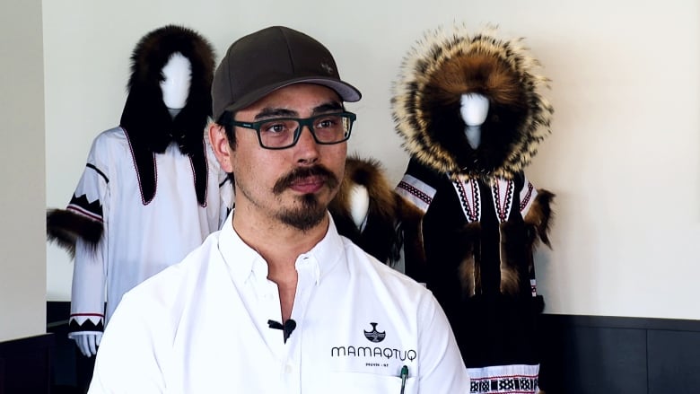 A portrait of a man in front of traditional Inuvialuit clothing.