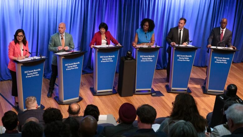 candidates stand at podiums