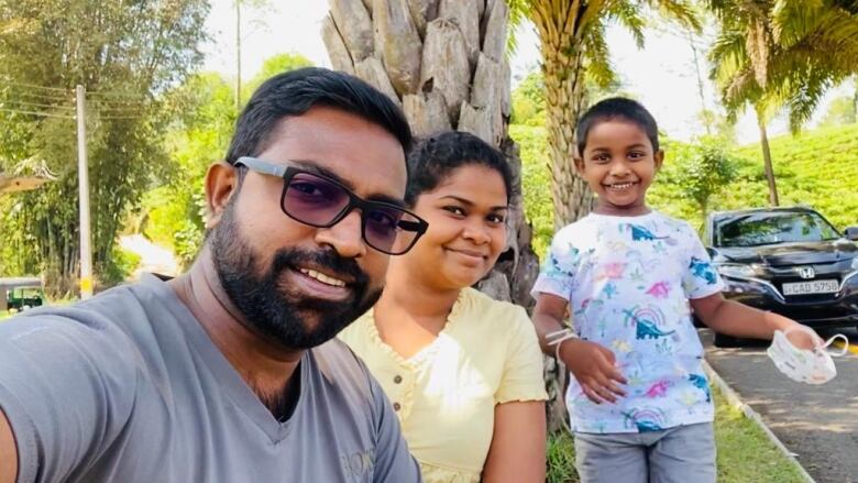 Surrey, B.C. resident Rukshani Jayasinghe, centre, is seen in a photograph by a street outdoors with her husband Nadeesh Gallage, left, and their five-year-old son Yevon, right. 