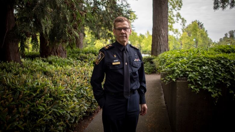 A man wearing a police uniform poses in a park.