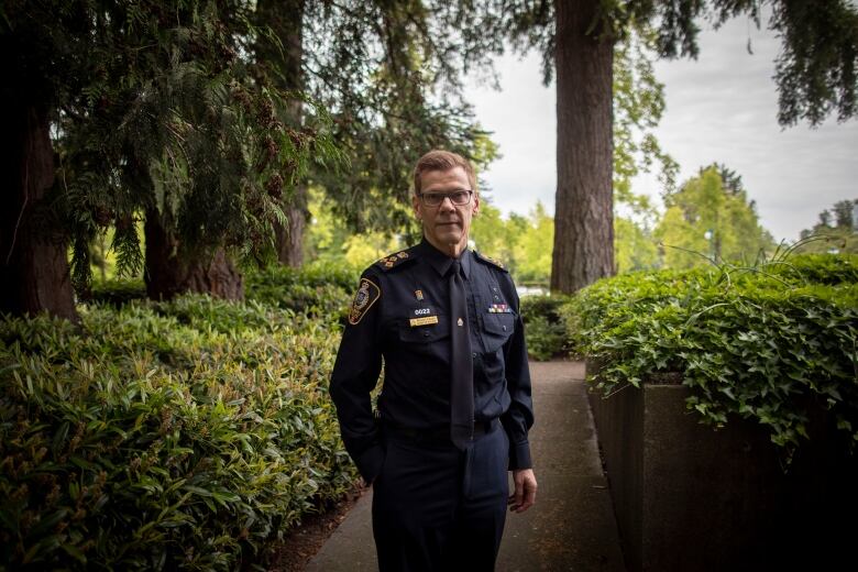 A man wearing a police uniform poses in a park.