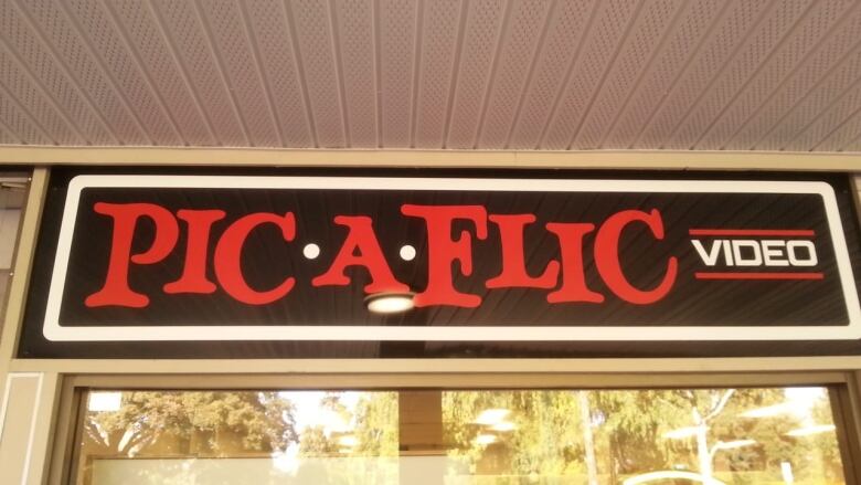 Image shows a black sign with red writing that spells out Pic-A-Flic.