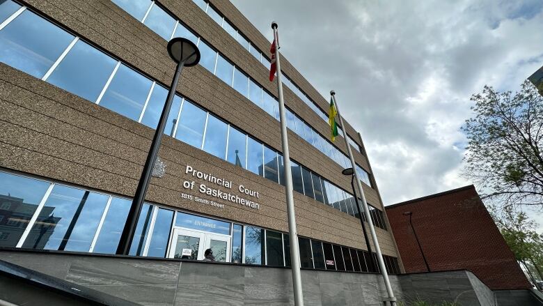 A grey court building with flags blowing in the wind. 