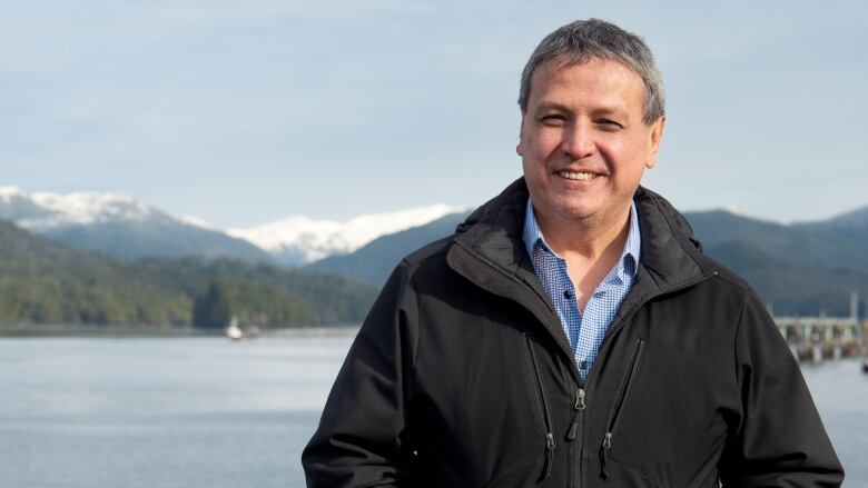 A man stands in front of open water