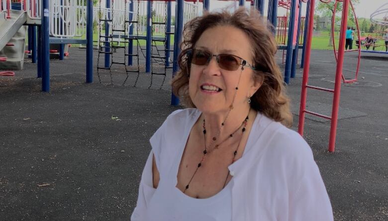 A woman at a playground smiles for the camera.