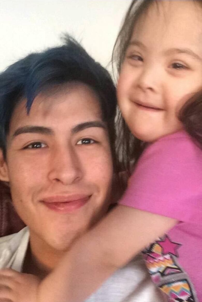 A young man holds a smiling little girl.