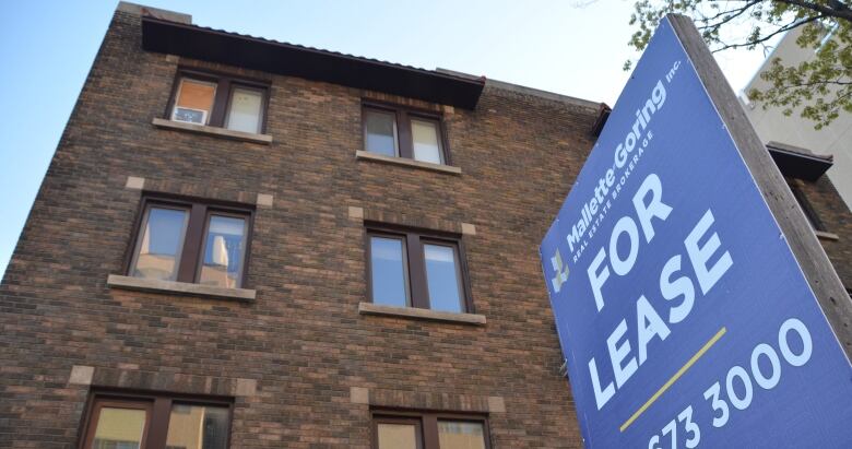 A four-storey brick office building has a for sale sign in front of it