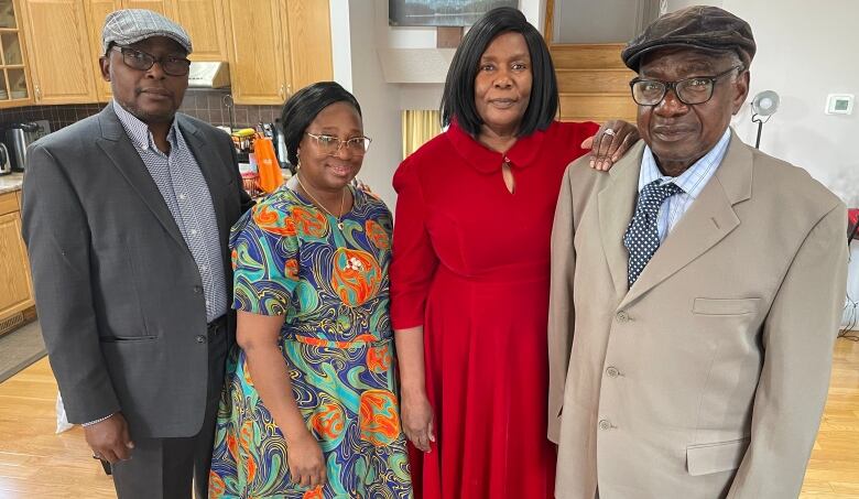 A group of cancer survivors and family members stand in the home of Yanika Oladele.