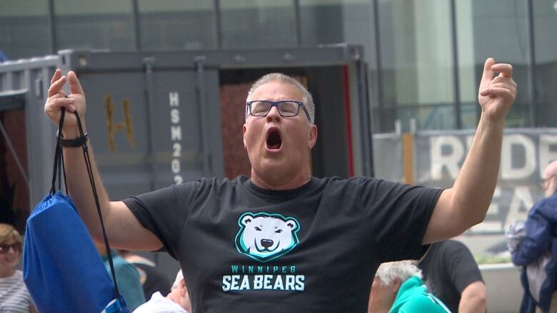 A white man with short grey hair lets out a cheer. 