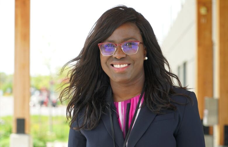 A close up portrait of a woman wearing glasses and a colourful blouse.