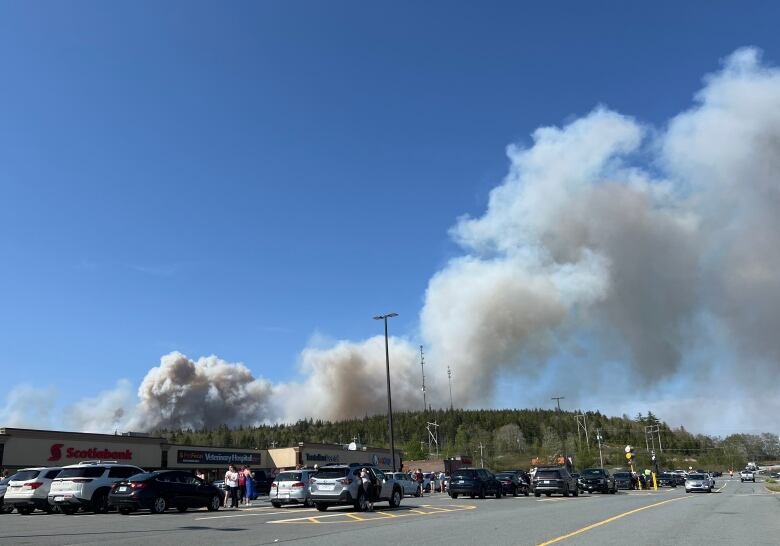 Smoke from a wildfire is shown in the background of a photo of a  strip mall.