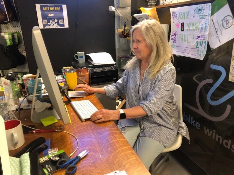 A woman wearing a white striped shirt sitting at a computer