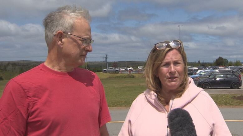 A man and a woman speak into a microphone.