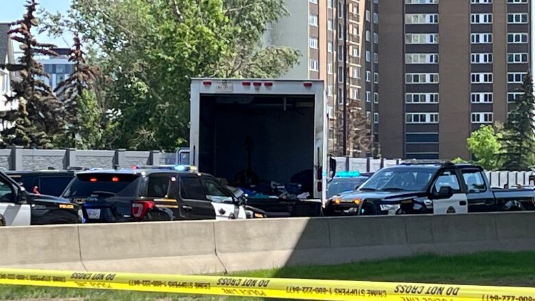 Several police vehicles and a cube van are stopped on a busy Calgary road. 