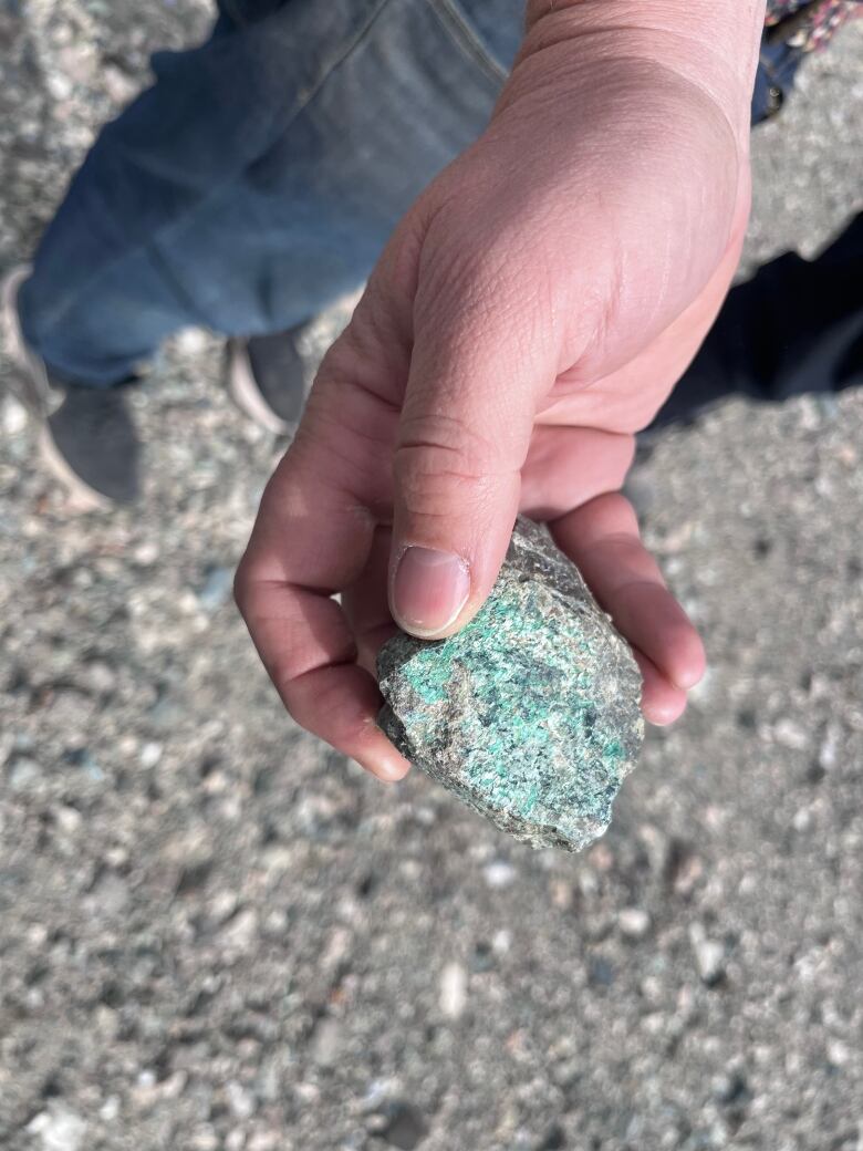 A hand holds out a grey stone tinted with blue.