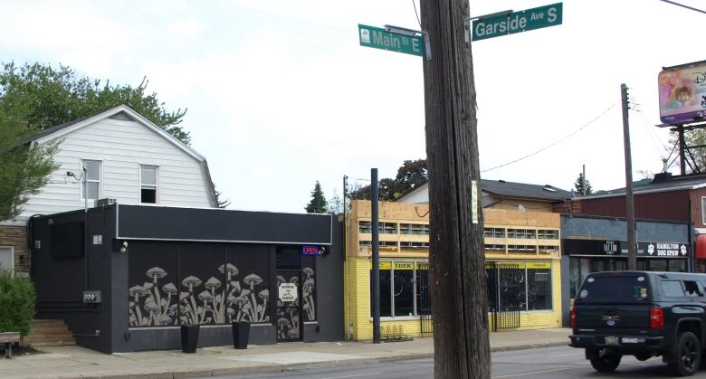 A series of storefronts. One has a bunch of pictures of mushrooms on it.