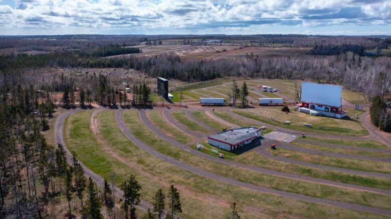 An aerial photo shows the Brackley Drive-in from above. There are two large screens in a field and only two small, skinny trees between them.