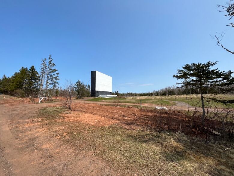 The large screen stands in an empty field with very few trees in sight.