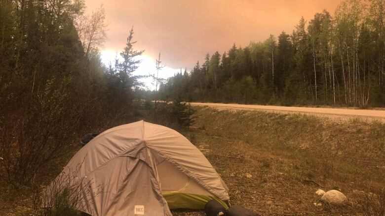 A tent along a road under a smoky sky.