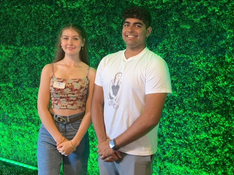 A young woman in a floral tank top and a young man in a white t-shirt.