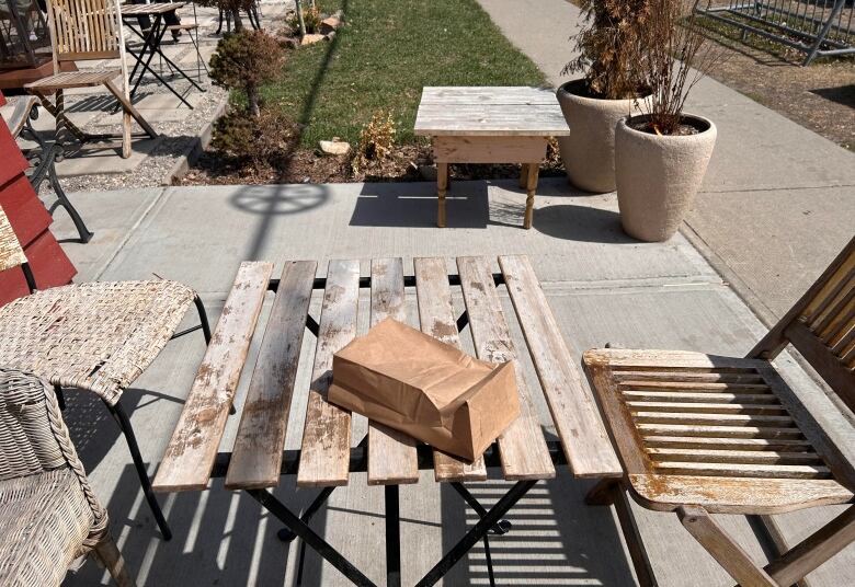 A brownbag sits on a wooden patio table. 