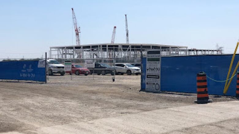 An industrial site with cranes in the air and a metal structure surrounded by a fence.