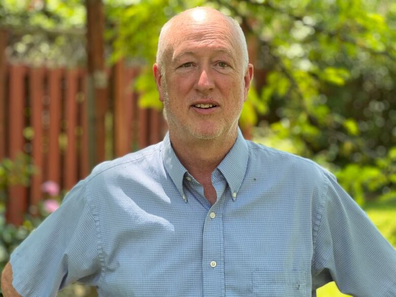 A man in a blue shirt stands outside