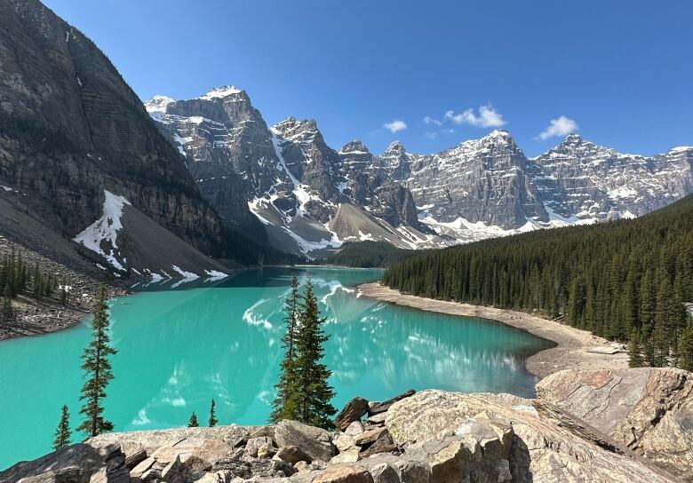 A turquoise lake surrounded by moutains on a clear day.