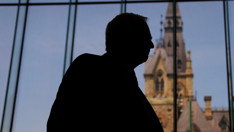 A man stands silhouetted in front of a view of Parliament in Ottawa.