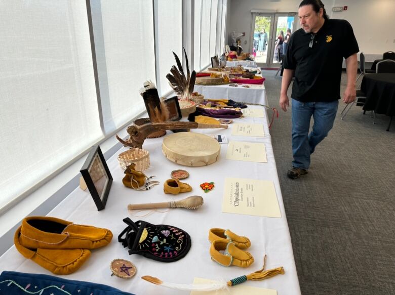 A collection of items including hand drums and bags sit on a table.