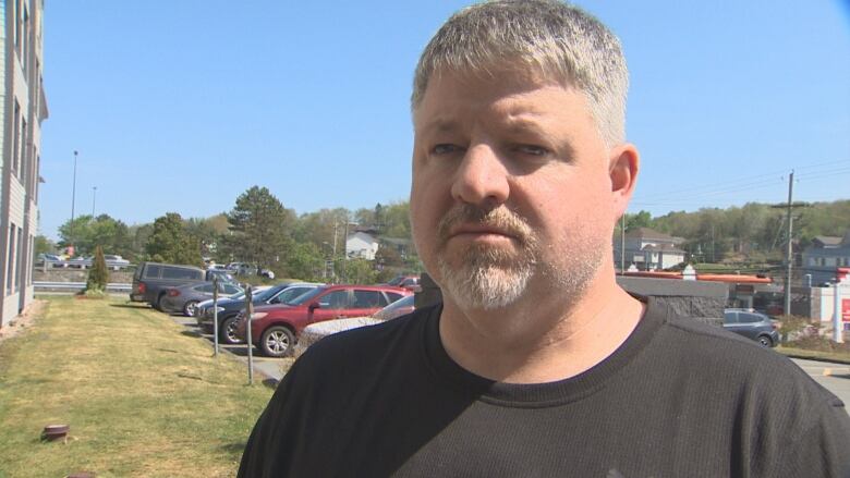 A man in a brown t-shirt speaks to the camera