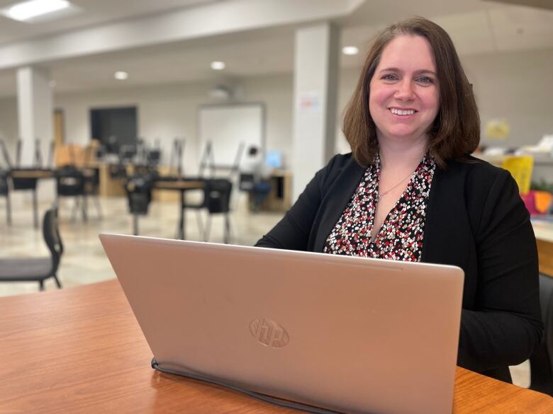 Sarah Jane Dixon, head of the English department at Three Oaks Senior High, sits in the school library with a laptop in front of her.  