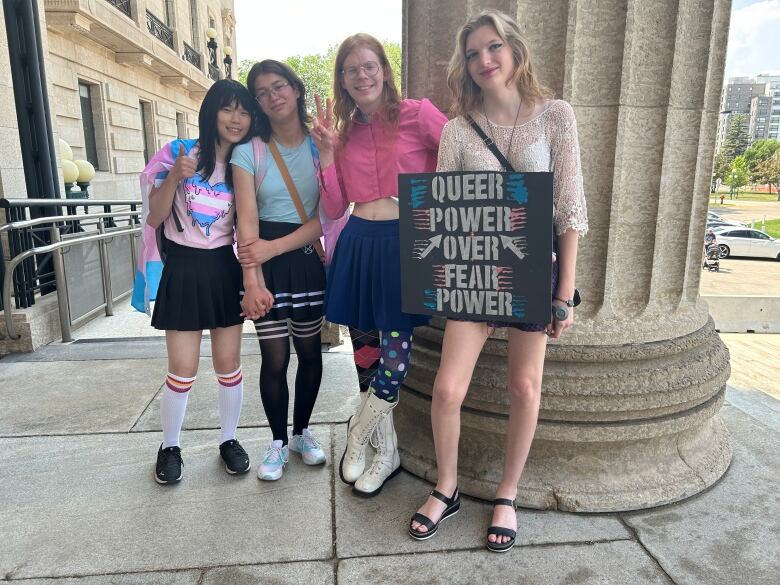 Four people stand side-by-side. One holds a sign that says 