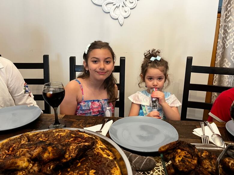 Two little girls at a dinner table 