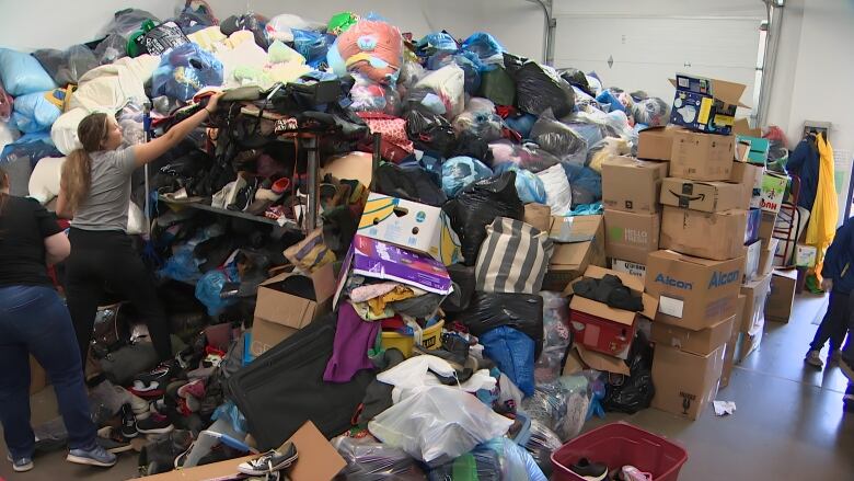 A massive pile of donations such as bags of clothes, boxes, household items, toys, shoes, etc. is just about reaching the ceiling. 