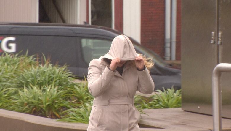 Woman in coat with the hood pulled down over her face.  