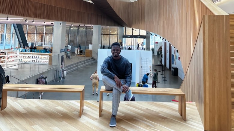 A man sits on a bench in the lobby of the Calgary Public Library's central branch. 