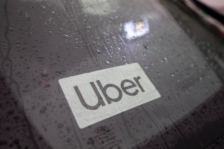 A rainy car dashboard with an 'Uber' sticker on it.