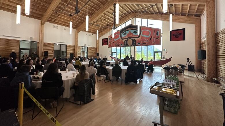 People sit at tables inside a large room.