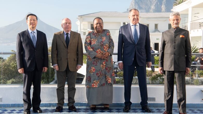 The ministers line up outside on a tiled deck. The mountains of Cape Town are seen in the background. 