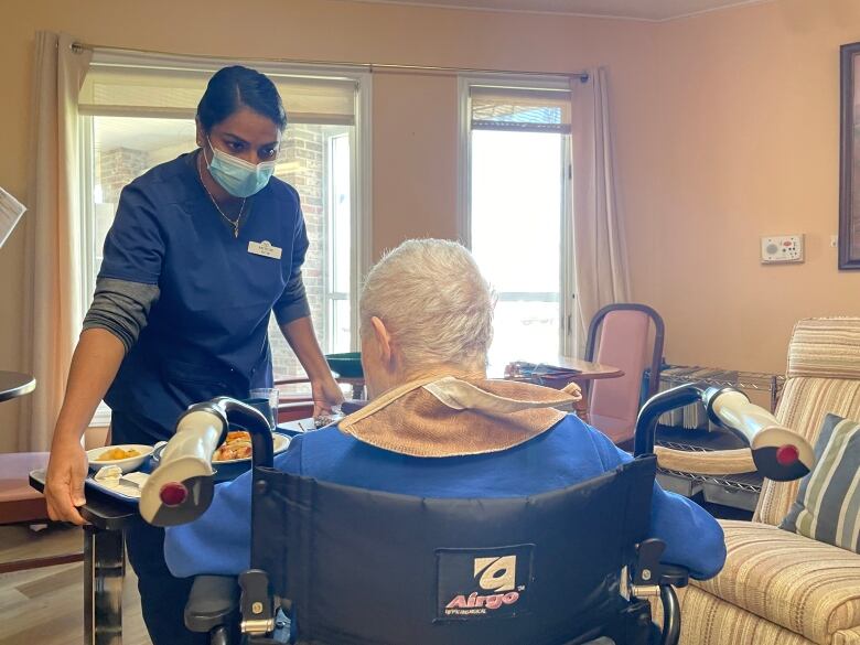 A caregiver at Whisperwood Villa long-term care home delivers a meal to a resident.