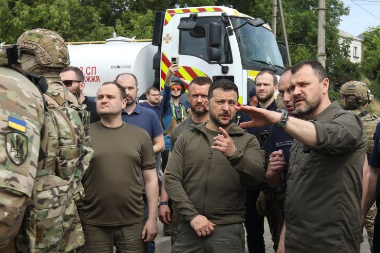 Soldiers on the left stand near other men.