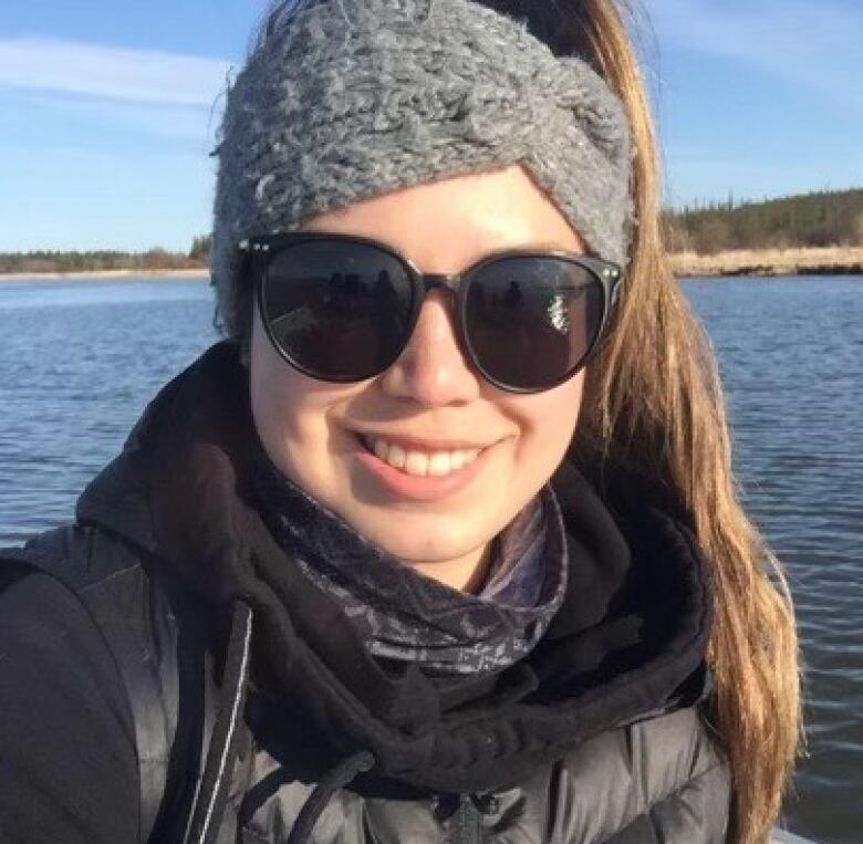 Smiling woman in shades by lake. 