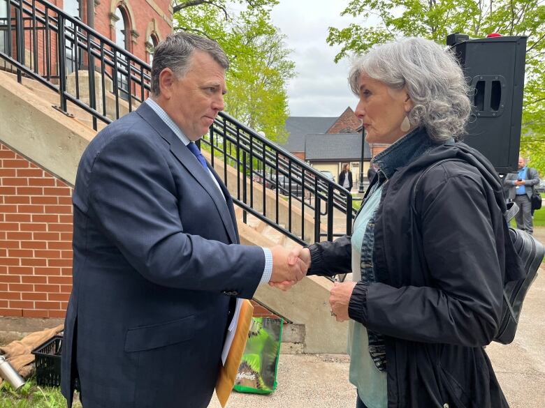 Premier Dennis King shakes hands with rally participant Joan Dyment.