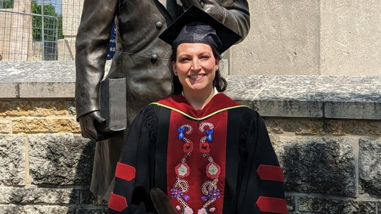 Laura poses in front of a statue in her beaded robes. 