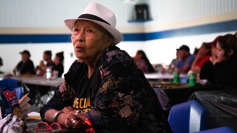 An olderwoman purses her lips watching a hockey game.